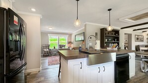 A modern kitchen with white cabinetry, a stainless steel refrigerator, and a built-in dishwasher. - KY Lakeshore Retreat -Waterfront Views, Dock, Deck, Large Parking -NEW 2024 (New Concord)