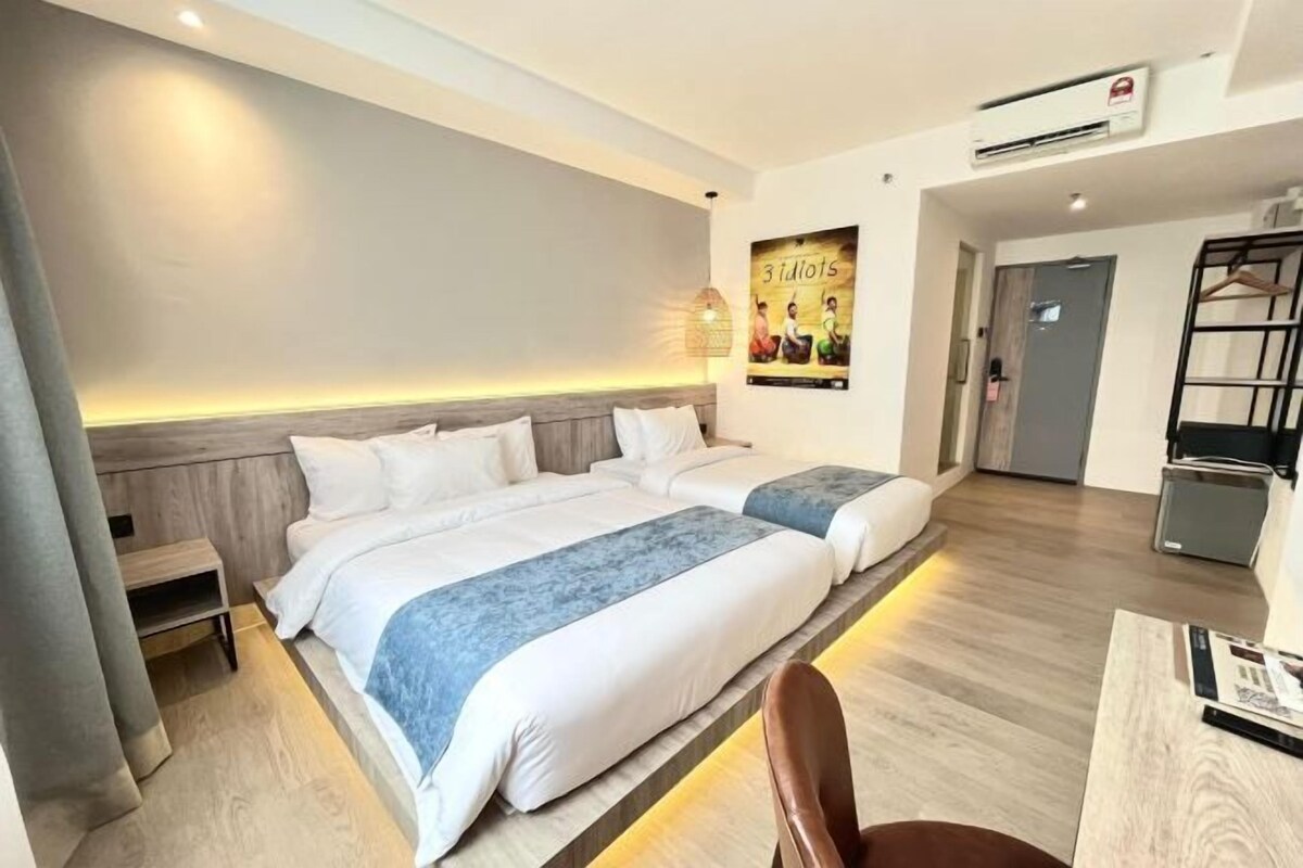 A hotel room with two beds, a desk, and a chair.