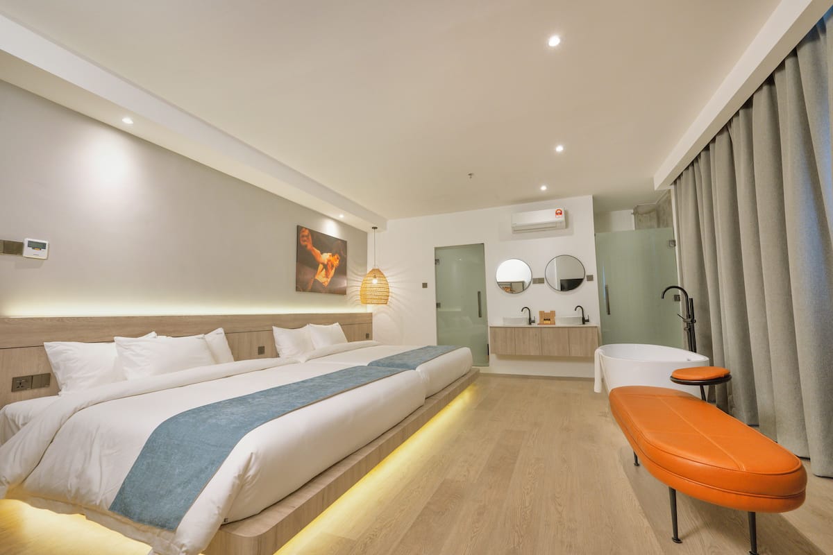 A modern hotel room with a large bed, a small bathroom, and a seating area.