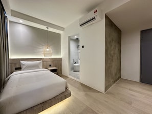 A modern hotel room with a large bed, a bedside table, a hanging light fixture, and an air conditioning unit. - Theatre Hotel  (Kuching)