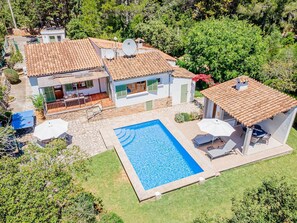 Um imóvel residencial com piscina, antenas parabólicas e um terraço de pedra.
