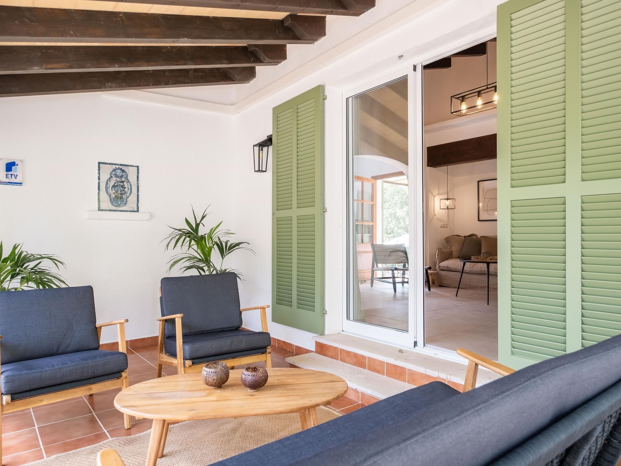 A cozy living area with a sofa, two armchairs, a wooden coffee table, and a view through a glass door to an adjacent room.
