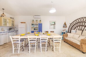 A compact living space with a dining area, kitchenette, and a cozy seating area with a wicker sofa. - Villa Turris - Alliste ,Apulia (Alliste)
