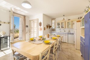 A kitchen with a wooden table set for dining, a blue refrigerator, and cabinets with glass doors.