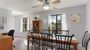 A dining area with a wooden table, chairs, and a ceiling fan. - Marsh and Ember Cottage (Brunswick)