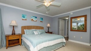 Un dormitorio con cama, dos mesitas de noche, ventilador de techo y decoración en la pared.