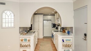 Cocina con alacenas blancas, una isla central y piso de baldosas.