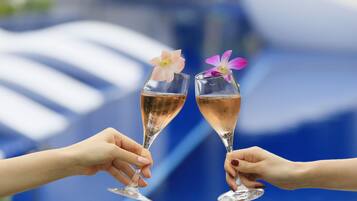 Zwei Sektgläser mit Blumen, von Händen gehalten, vor unscharfem Hintergrund.
