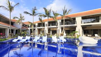 Uma área de piscina de hotel com várias espreguiçadeiras e palmeiras.