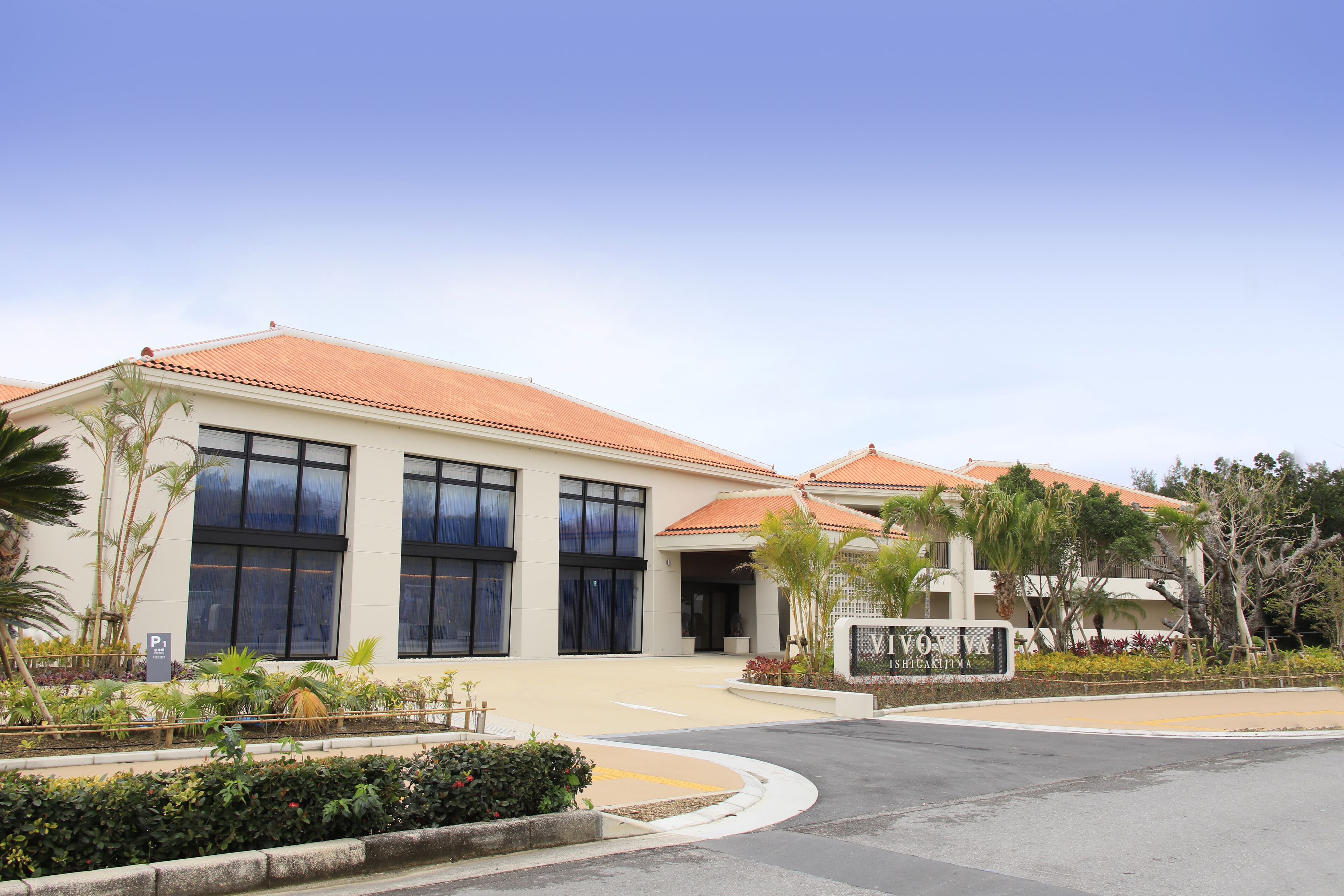 A building with a tiled roof, large windows, and a landscaped area with plants.