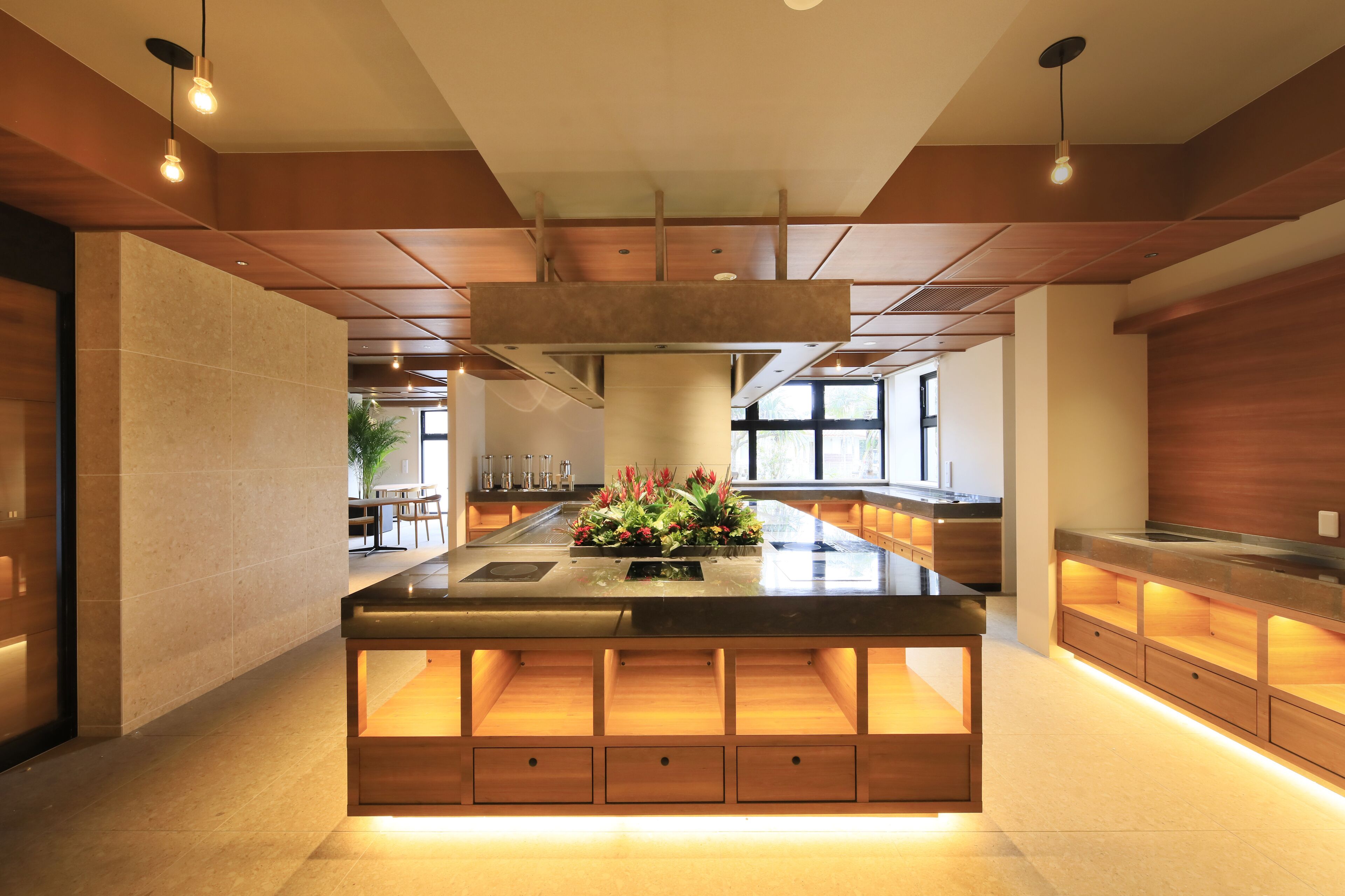 A modern kitchen with a central island, wooden cabinetry, and pendant lighting.