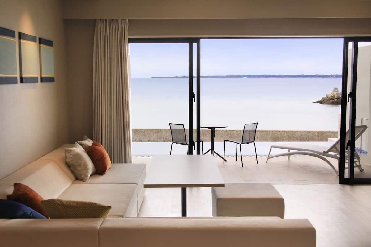 Un salon moderne avec un canapé, une table basse et un balcon offrant une vue sur la mer.