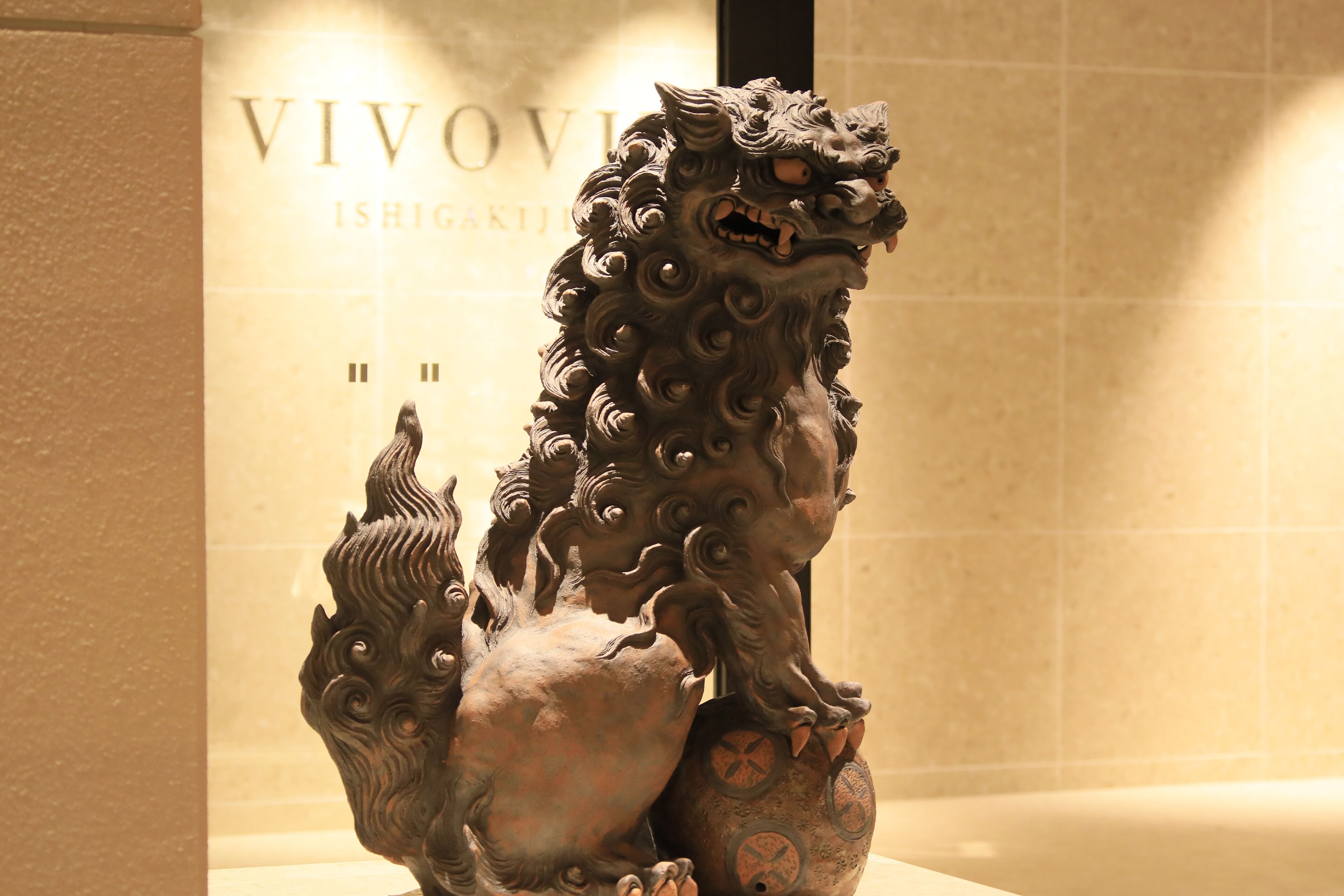 Eine Bronzelöwenstatue in einem Museumsambiente.