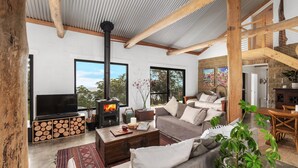 Una sala de estar acogedora con chimenea, sofá, mesa de centro y televisor.