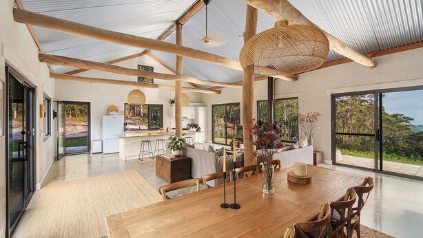 Amplia sala de estar integrada con una gran mesa de madera para comer, cocina y vistas al exterior.