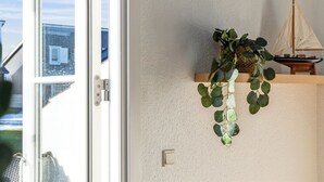 Ein Zimmer mit einer Schiebetür, einer kleinen Holzablage mit einem Modell eines Segelboots und einer hängenden Pflanze.