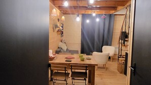 Un intérieur chaleureux avec une table à manger en bois, des chaises, un canapé et un escalier menant à un niveau supérieur.