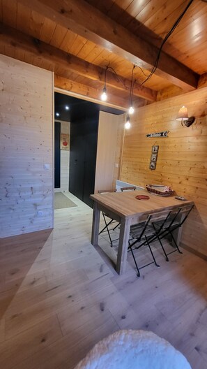 Un intérieur en bois avec une table à manger, des chaises et des luminaires suspendus.