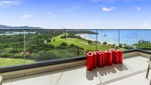 A balcony with a clear view of a golf course, beach, and ocean. - B1101 Modern oceanview 2 bedroom condo (Cupecoy)