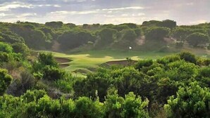 A golf course with a flagstick, surrounded by dense greenery.