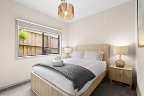 Quarto com cama, mesas de cabeceira, janela com vista e luminária pendente.