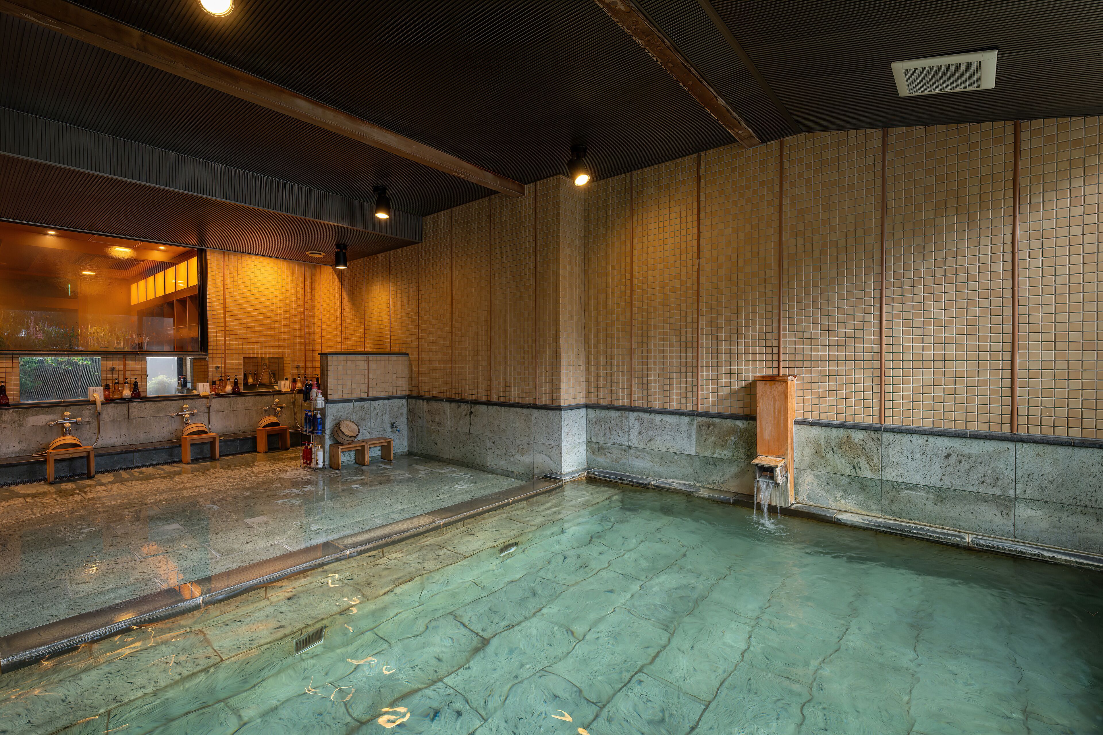 Un onsen japonés tradicional con un banco de madera, un armario pequeño de madera y una pared de azulejos.