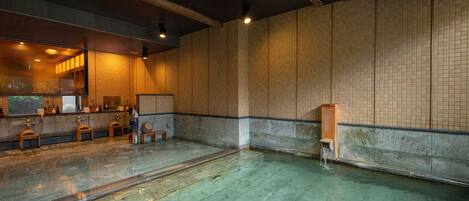 A traditional Japanese onsen with a wooden bench, a small wooden cabinet, and a tiled wall.