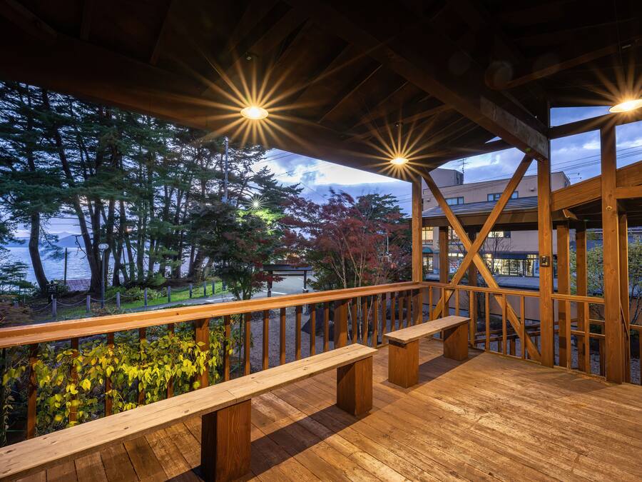 A wooden deck with benches, overlooking a body of water and trees.