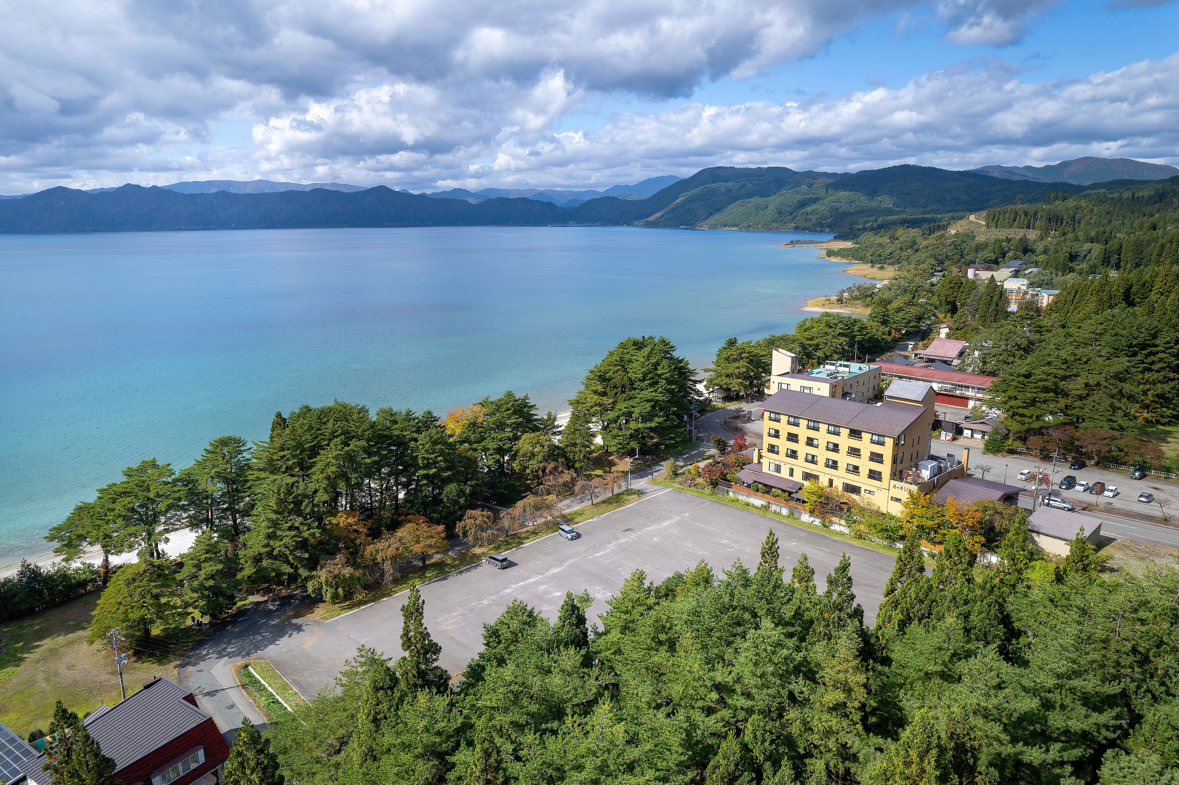 A coastal town with a large body of water, a parking lot, and buildings with a mix of architectural styles.