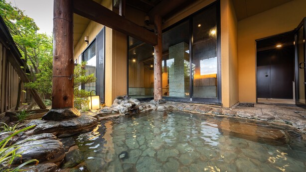 Un edificio tradicional japonés con una fuente de agua de piedra al frente.