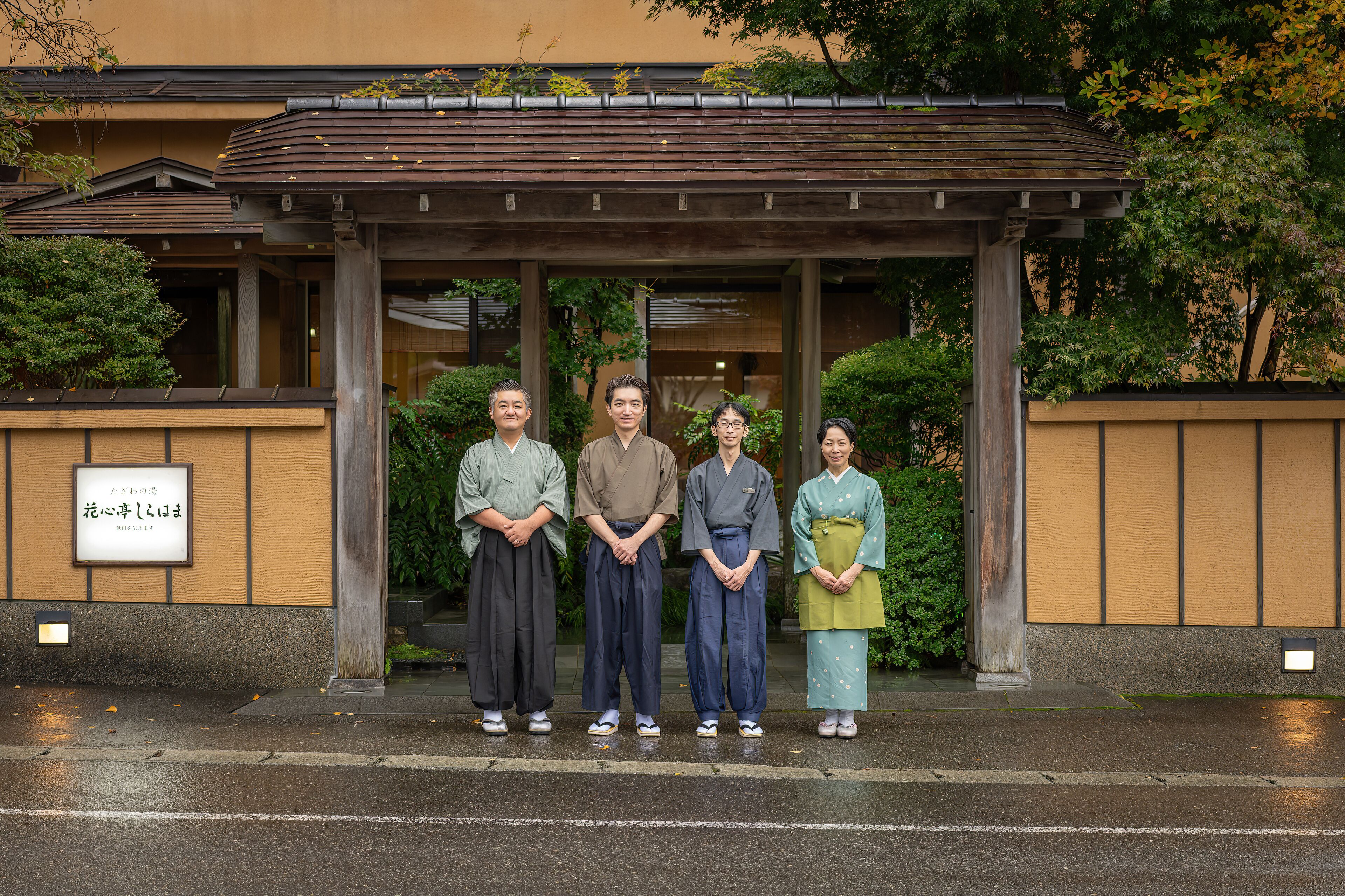 Un grupo de personas frente a un edificio de estilo arquitectónico tradicional, con estructura de madera y un cartel con caracteres japoneses.