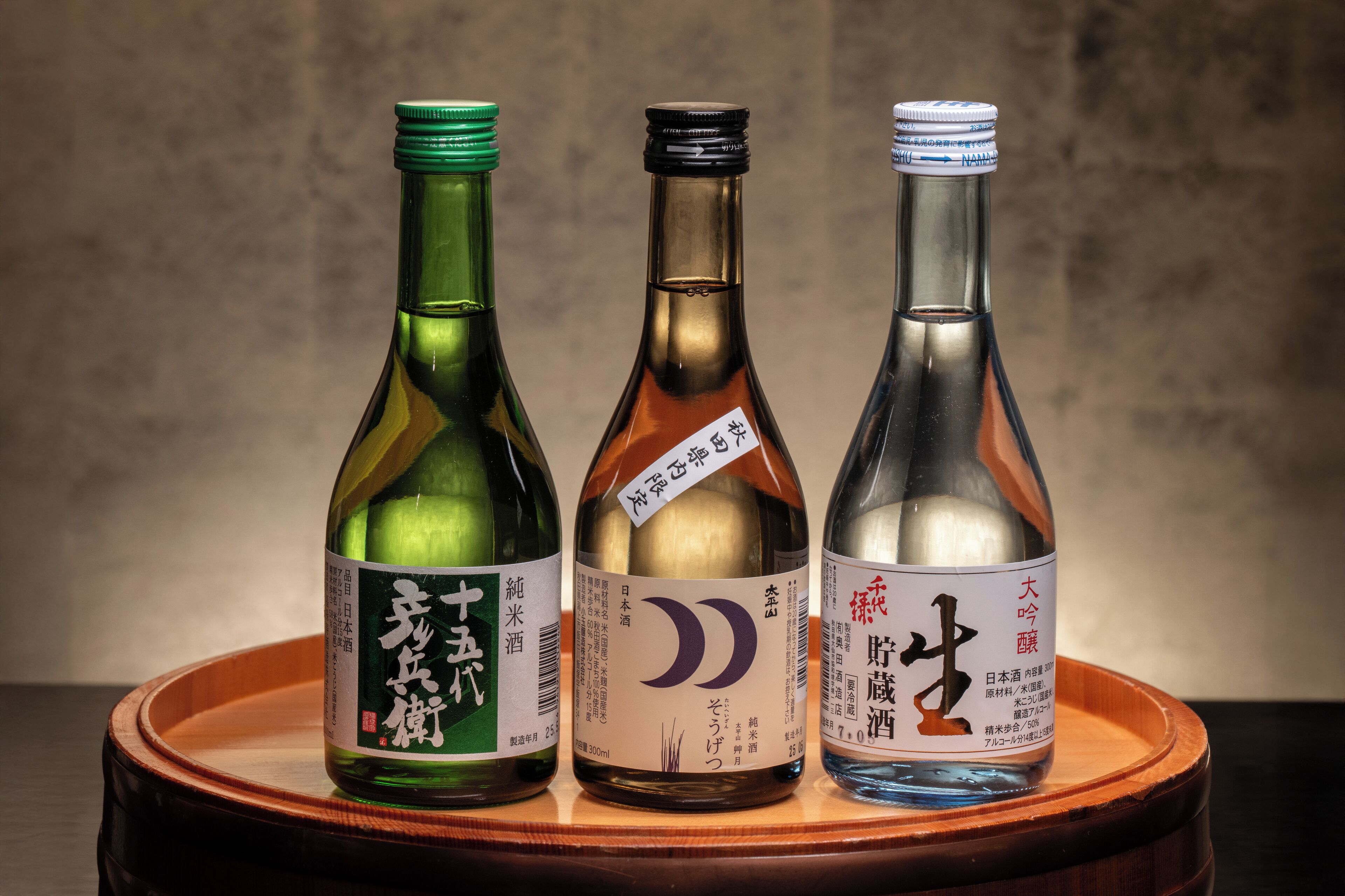 Three bottles of Japanese sake on a wooden tray.