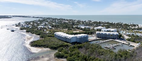Un complejo turístico frente al mar con varias edificaciones, un puerto deportivo y una playa.