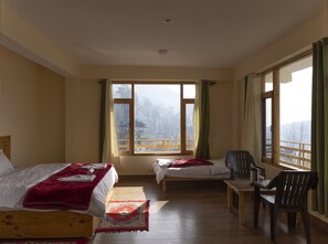 Relax in a serene mountain view room with two single beds, a wooden bench, and a chair.
