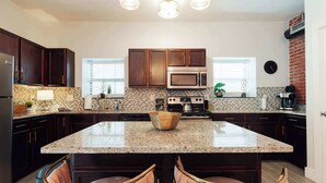 Una cocina moderna con armarios de madera oscura, una isla central y una estufa de acero inoxidable.
