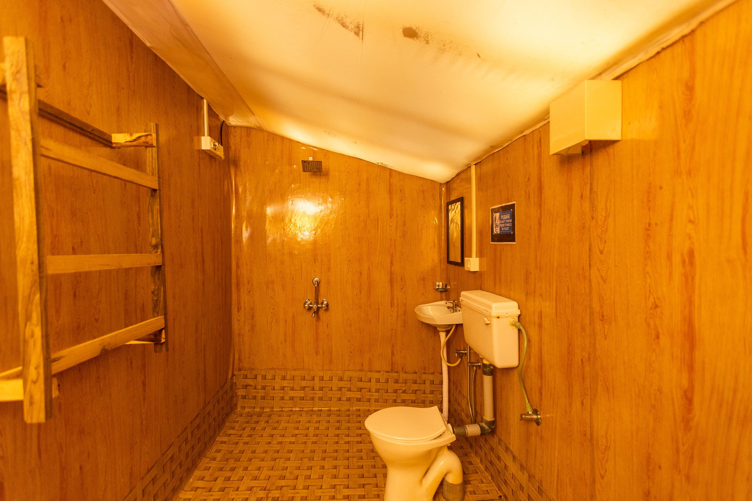 A wooden bathroom with a toilet, sink, and shower.