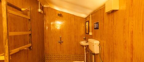A wooden bathroom with a toilet, sink, and shower.