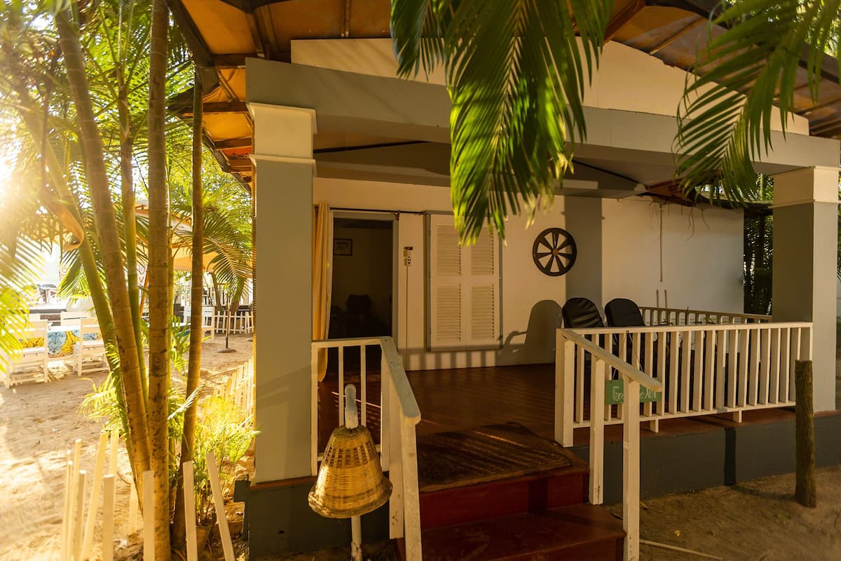 Uma área externa coberta com deck de madeira, grades brancas e um sino.