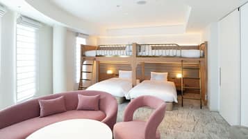 Et hotelværelse med køjesenge, en sofa, en stol og et lille bord.