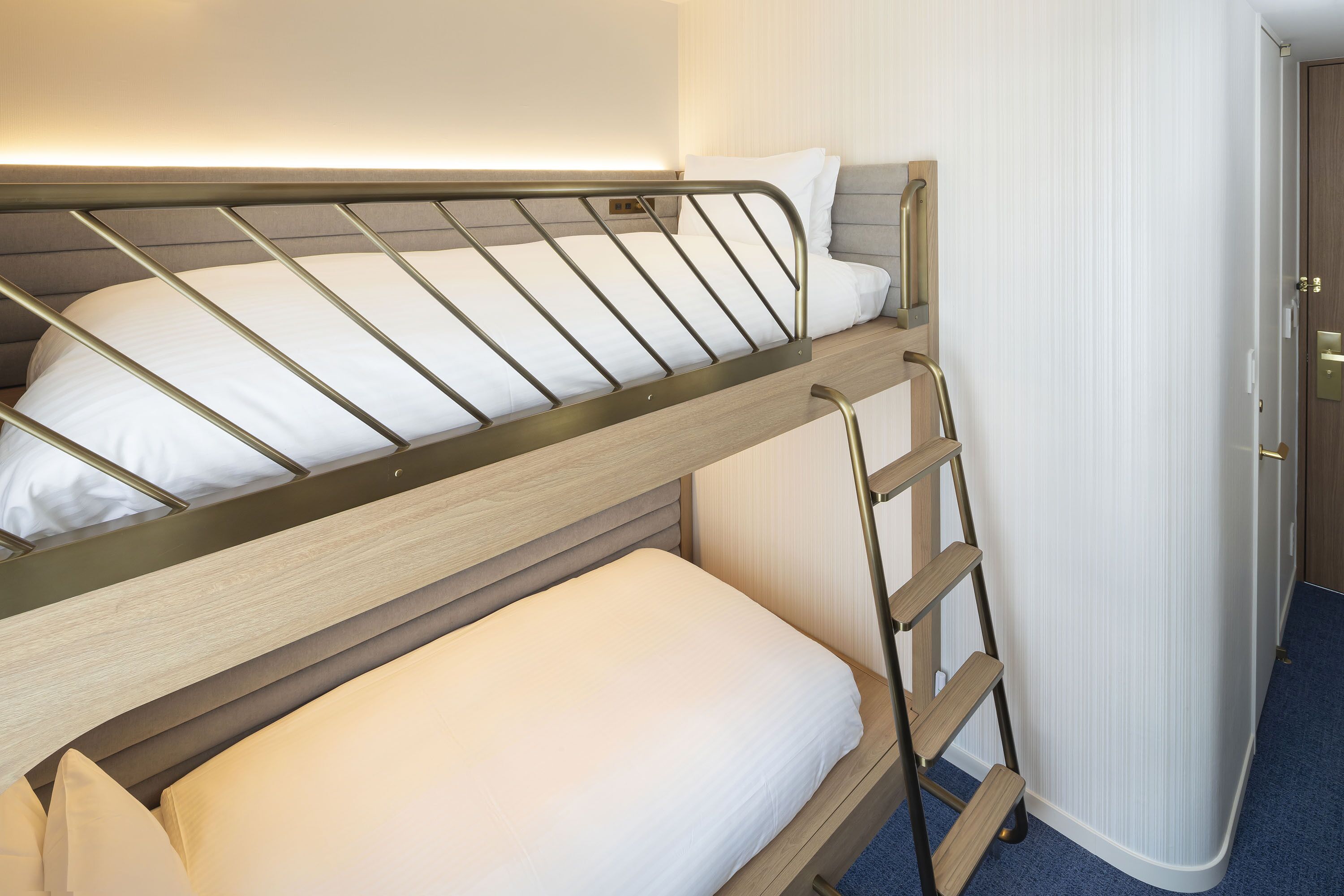 Un letto a castello con una scala, un comodino e una porta che dà su un bagno.