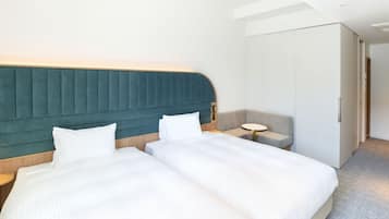 A hotel room with two beds, a small round table, and a wardrobe.