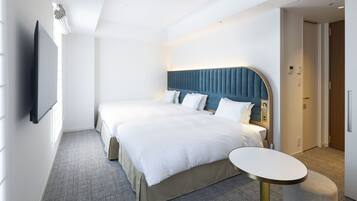 A hotel room with a large bed, a bedside table, a flat-screen TV, and a door leading to another room.