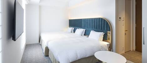 Habitación de hotel con una cama grande, una mesita de noche, un televisor de pantalla plana y una puerta que da a otra habitación.