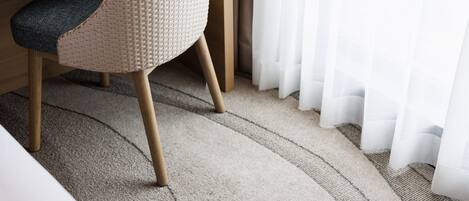 A carpeted floor with a chair and a bed in the foreground.