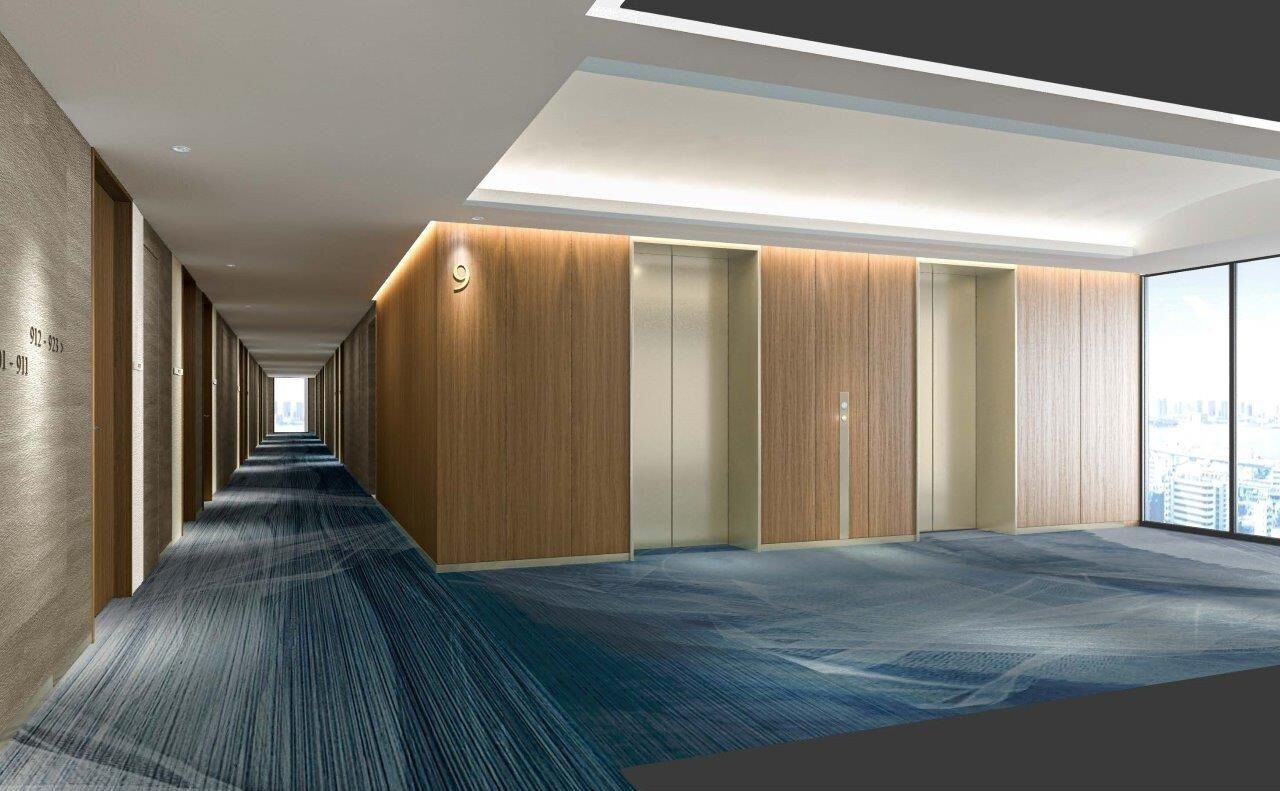 A modern hotel corridor with a long, straight layout, wooden paneling on the walls, and a carpeted floor.