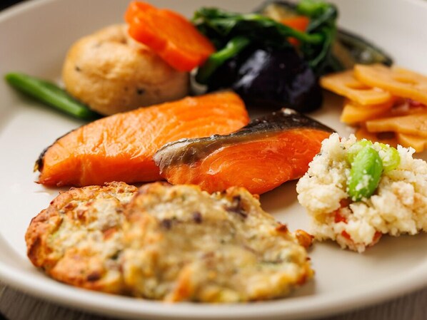 A plate with various foods including salmon, vegetables, and a potato.