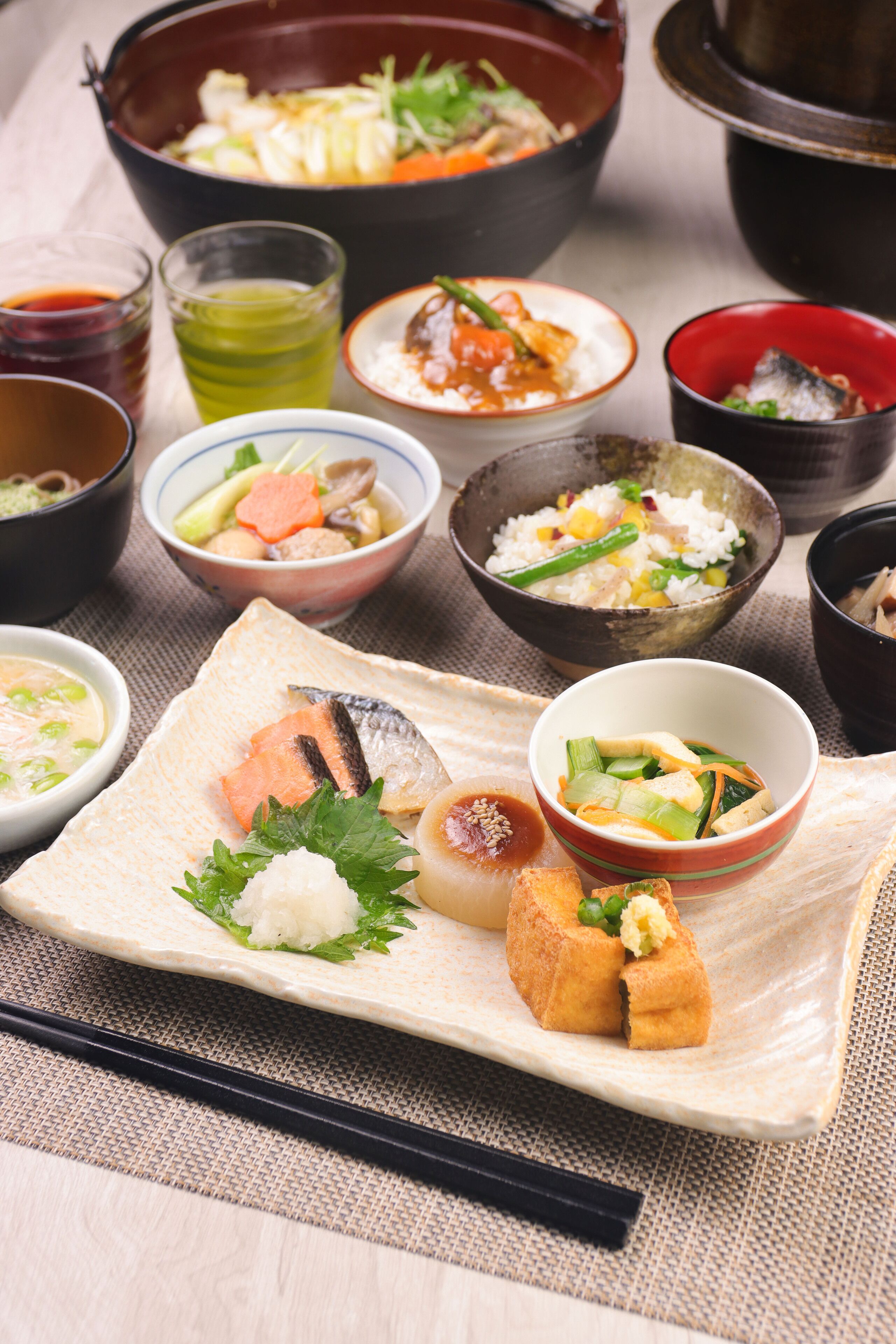 Diverse Japanse gerechten gerangschikt op een tafel, waaronder sushi, rijst en soep.