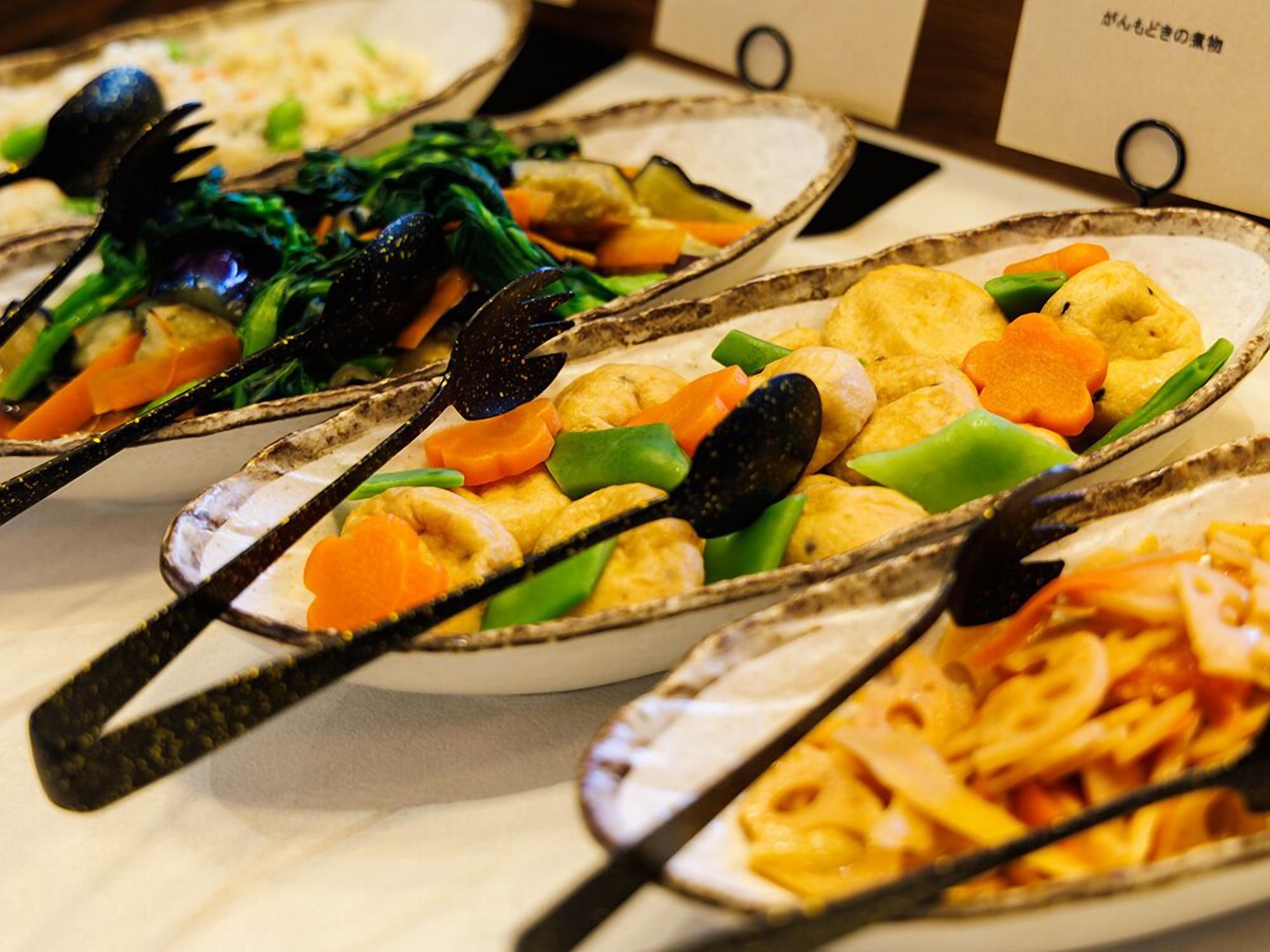 Une table de buffet proposant divers plats, notamment des pâtes, des légumes et des fruits de mer.