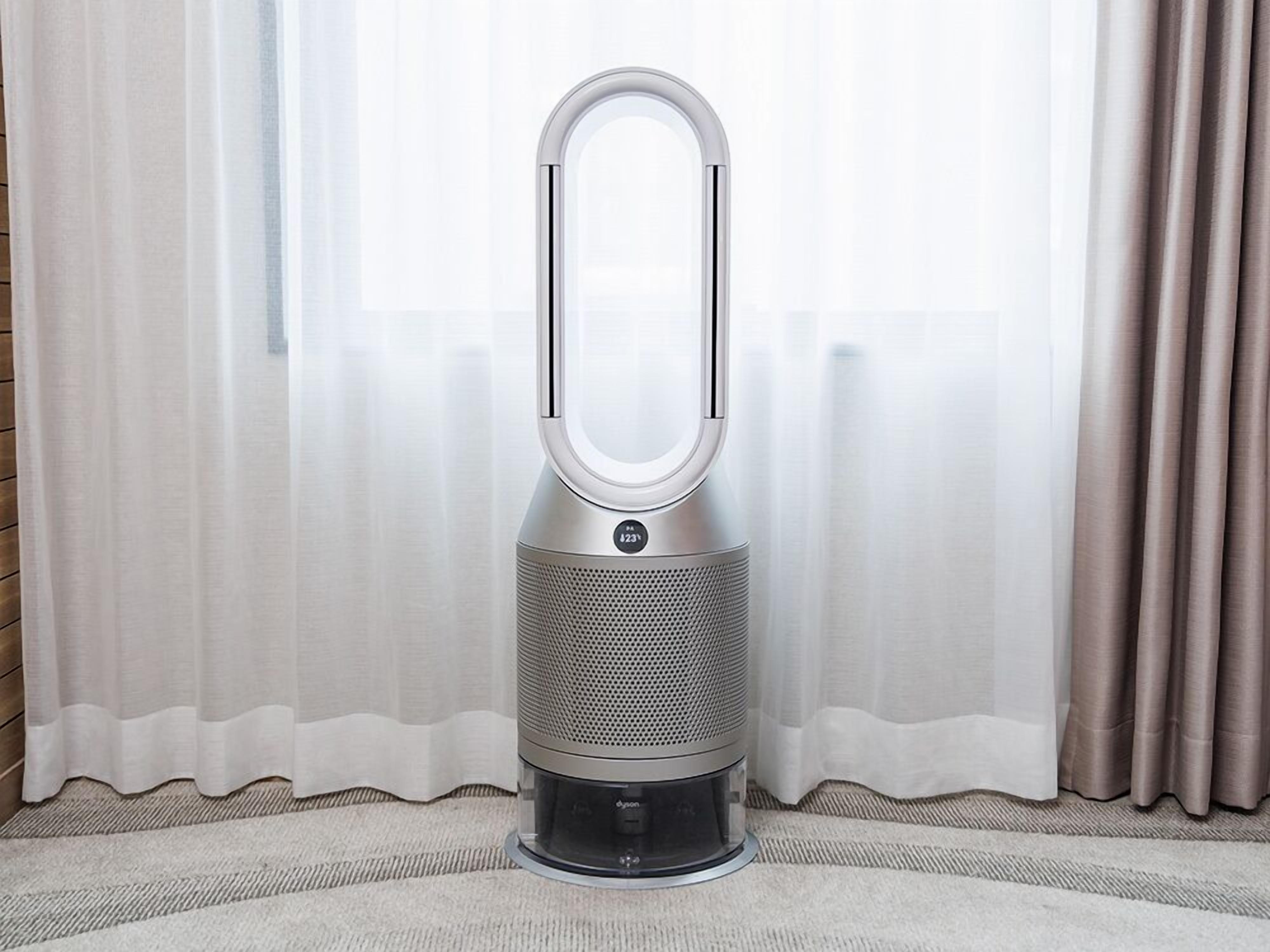 Un purificador de aire Dyson con cuerpo cilíndrico y parte superior circular, sobre un piso alfombrado.