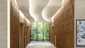 Un pasillo moderno con paneles de madera y techo curvo, que conduce a una puerta de cristal con vistas a zonas verdes.